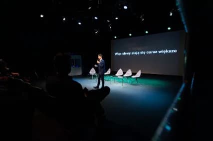 Scena sympozjum z prezentacja wyswietlona na ekranie